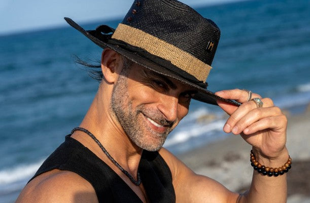 Man tipping the brim a custom made hat at the beach