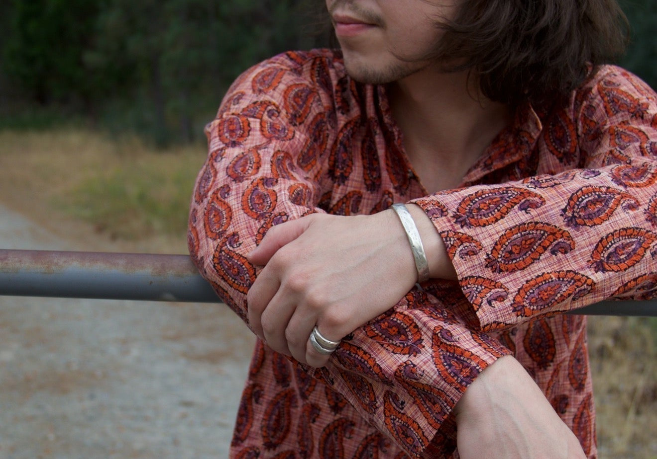Man with 1960's apparel and blue sunglasses wearing jewelry