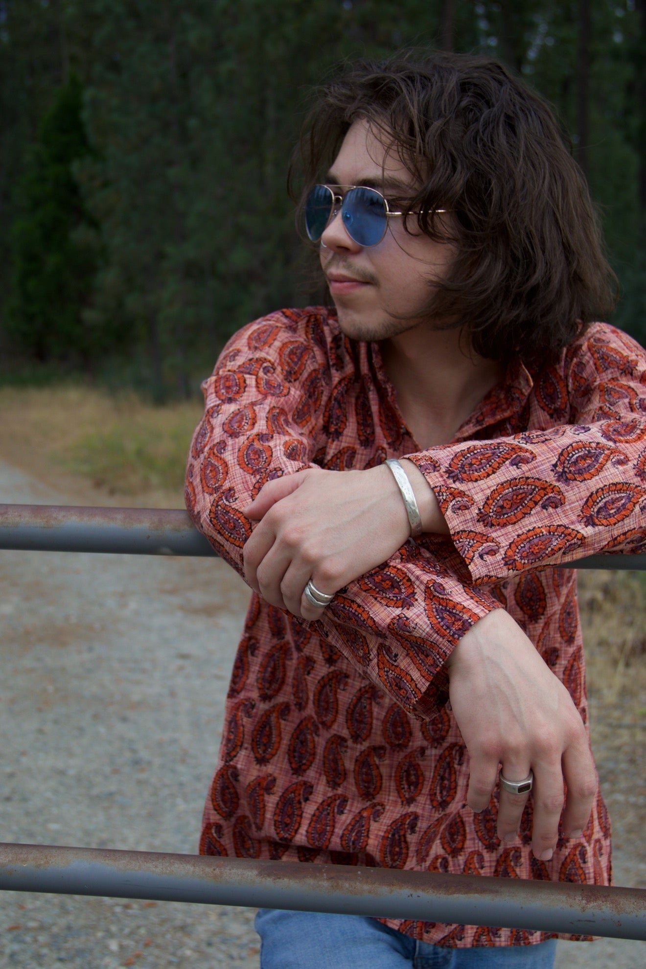 Man with 1960's apparel and blue sunglasses wearing jewelry
