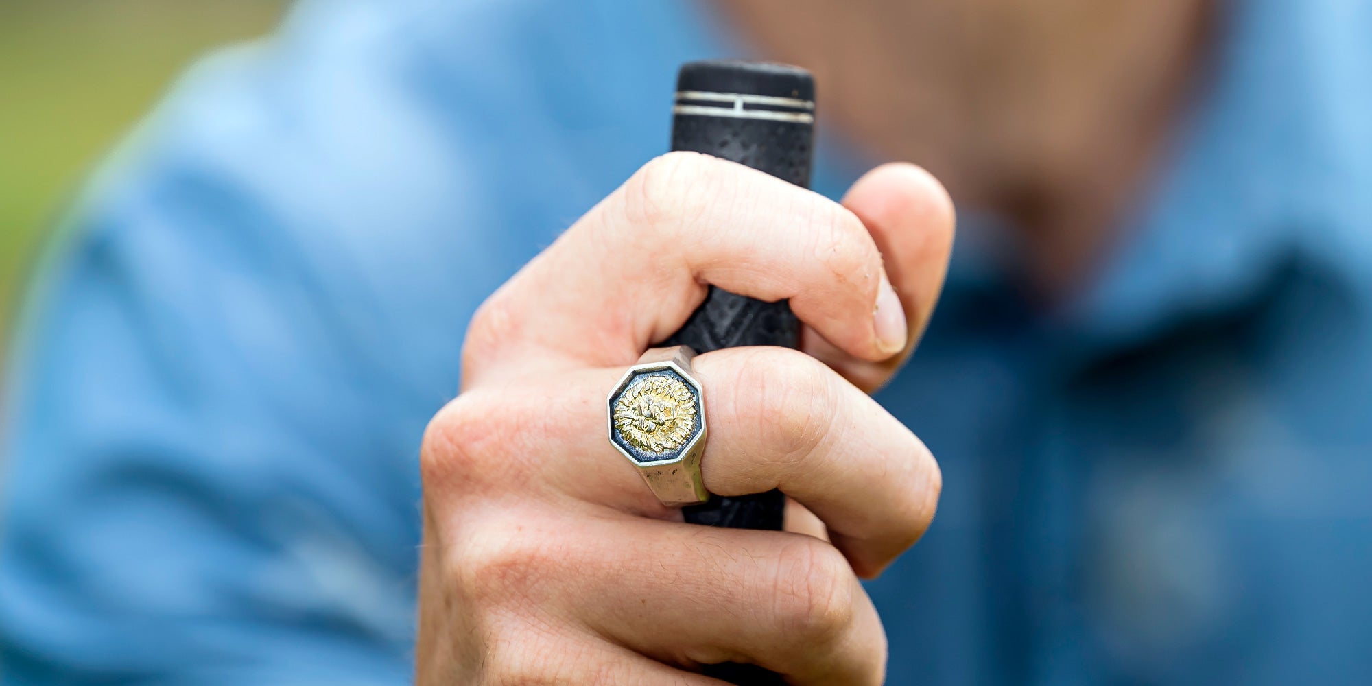 Man holding golf club wearing silver lion ring