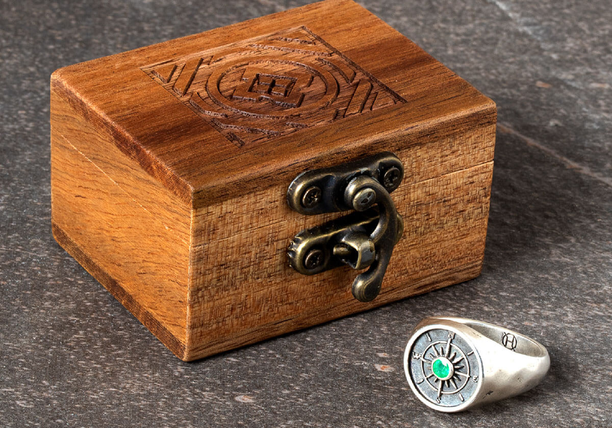Decorative, engraved Wooden box with a silver ring with an emerald on a dark surface