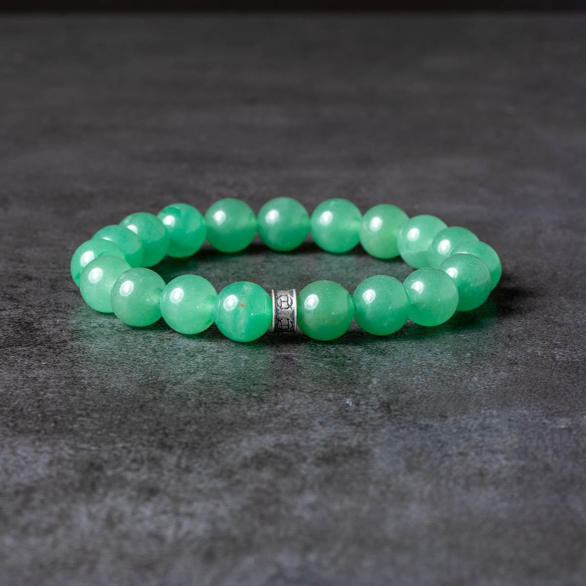 Green beaded bracelet on a dark gray surface