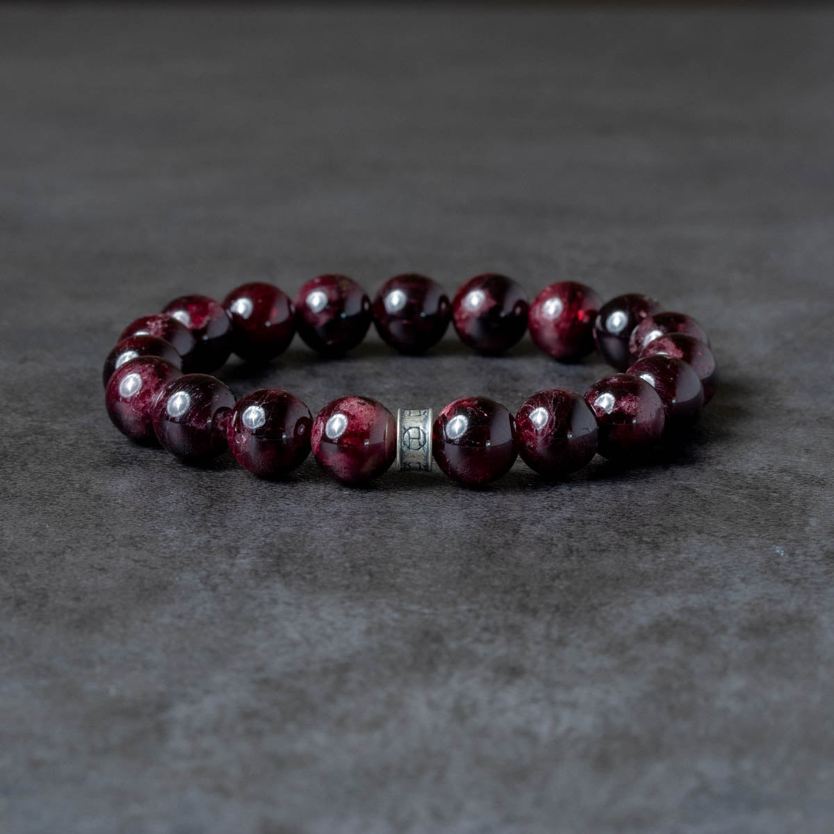 Beaded bracelet with red beads and silver accents on a dark gray background