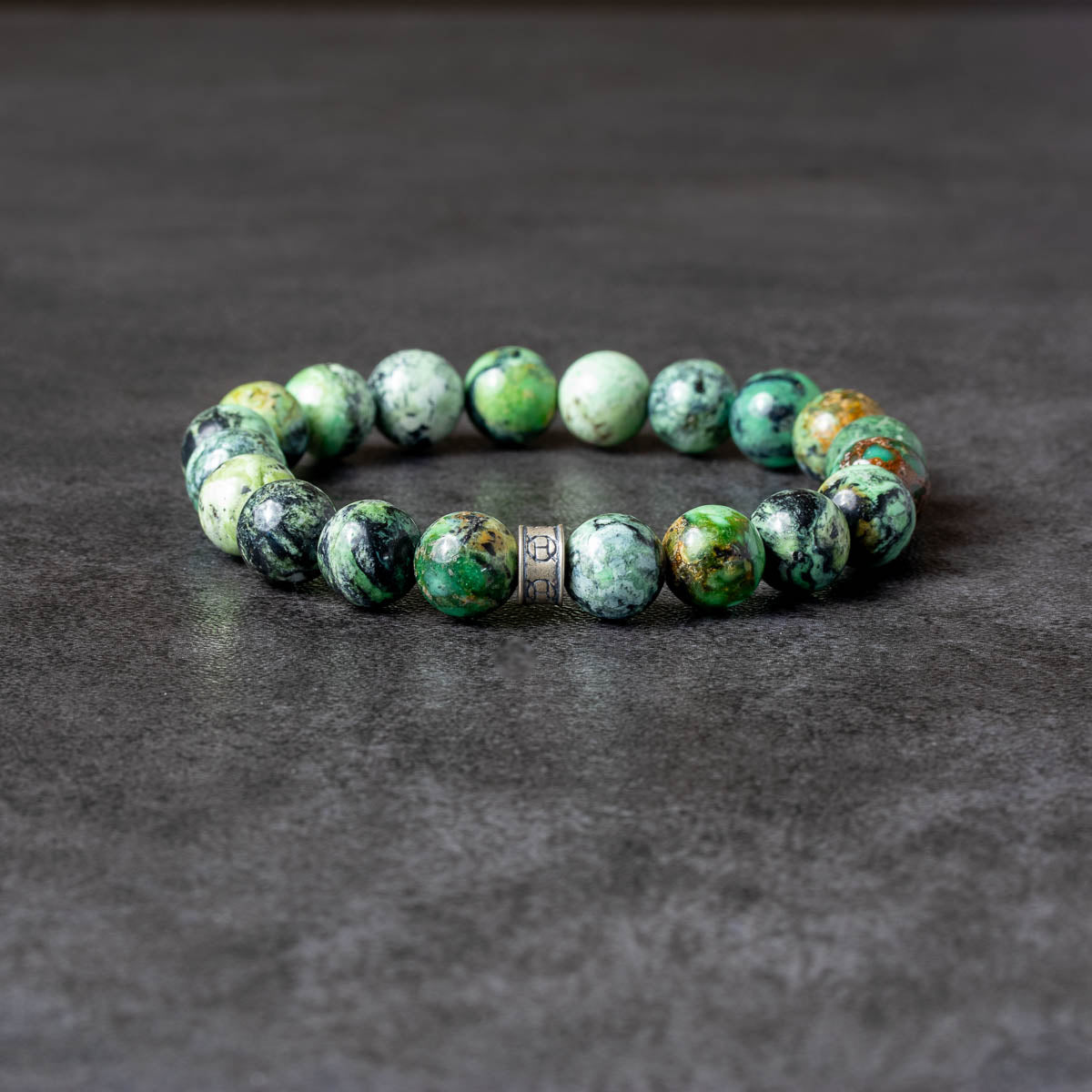 Green beaded bracelet on a dark gray background