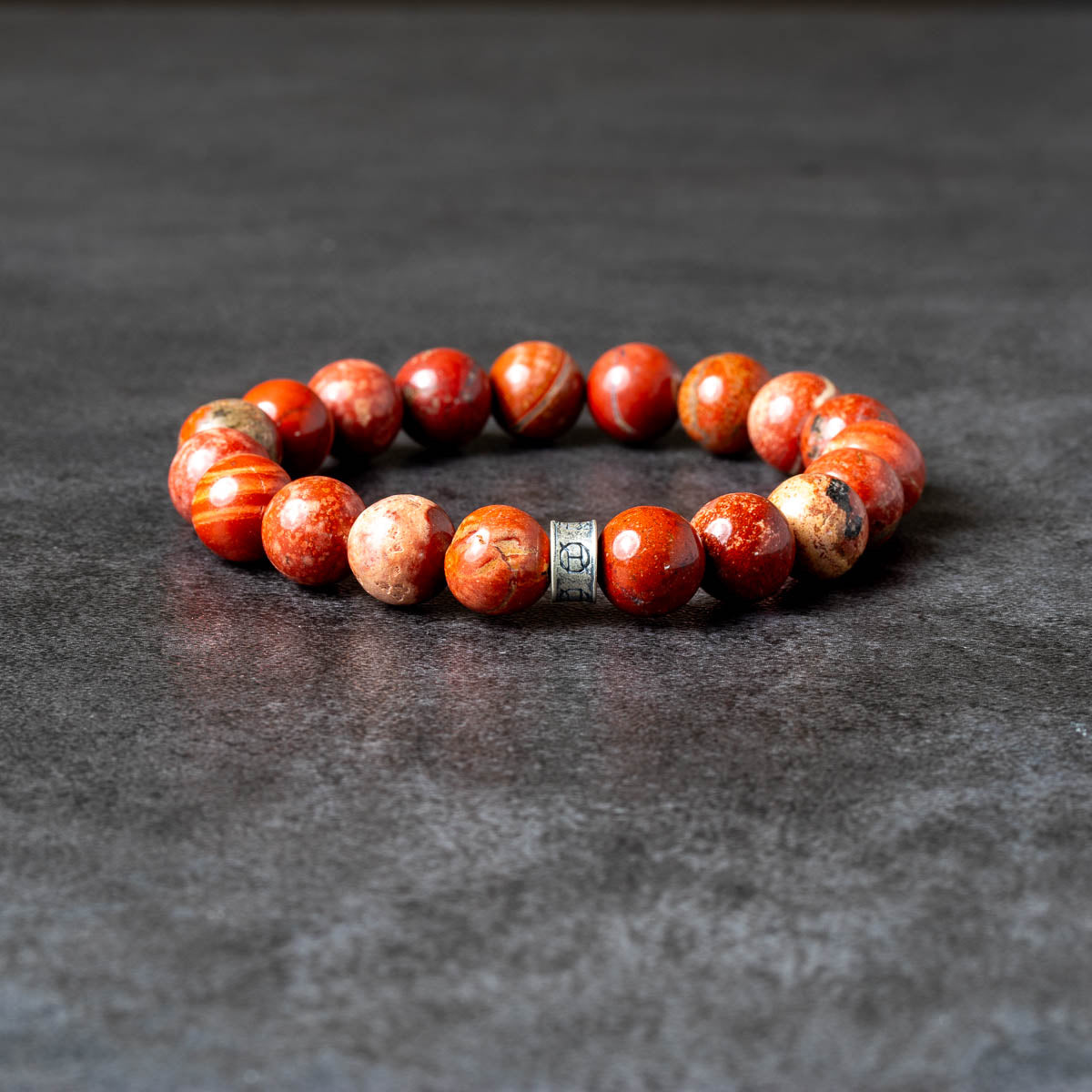 Red jasper beaded bracelet on gray background