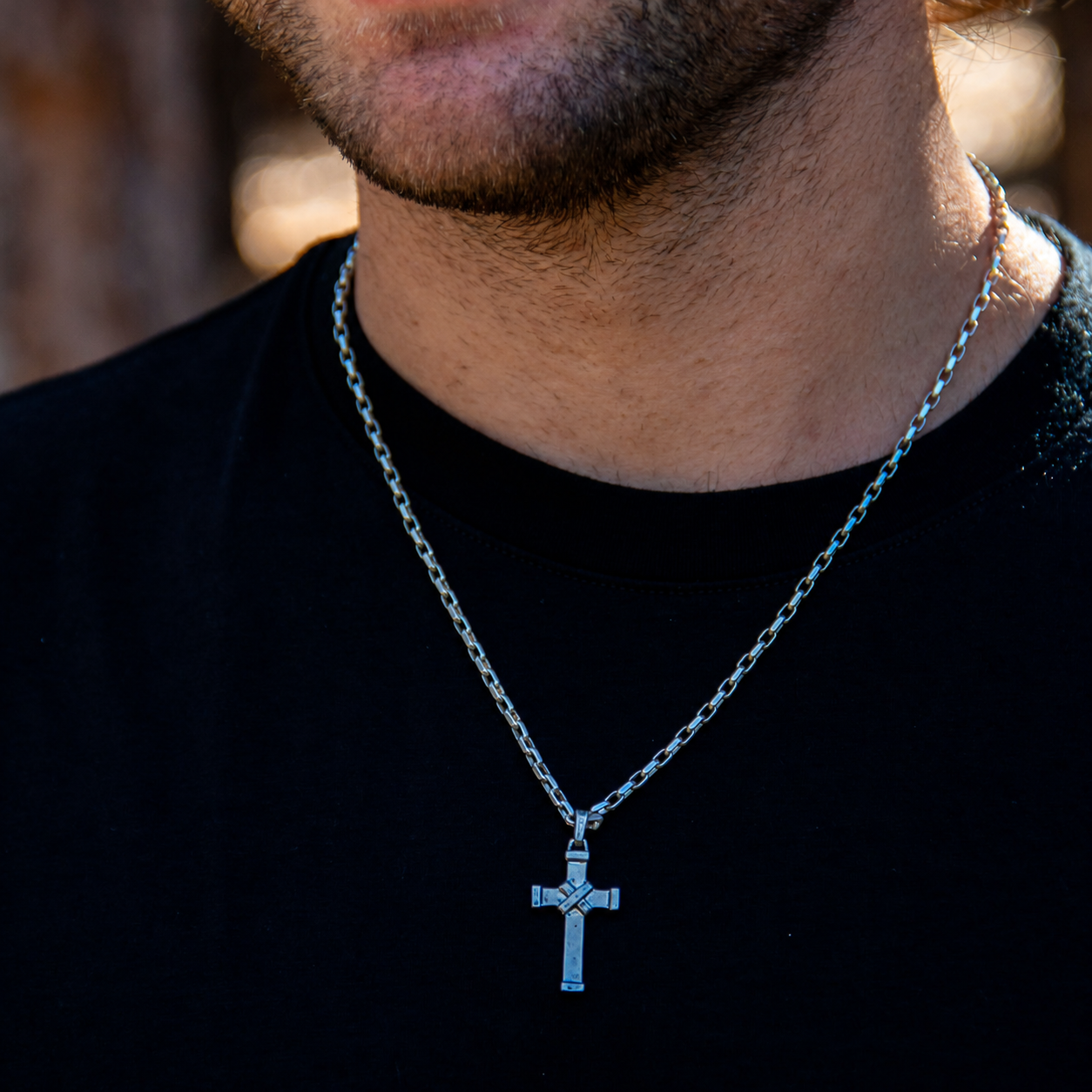 Man in black t-shirt wearing small silver cross pendant