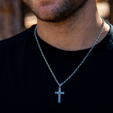 Man in black t-shirt wearing small silver cross pendant
