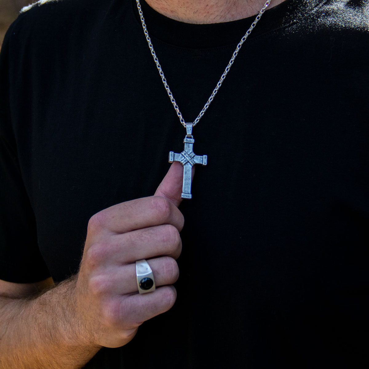Man in black t-shirt wearing large silver cross pendant