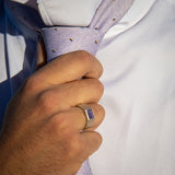 Man straightening necktie wearing lavender and silver signet ring