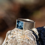 Silver ring with a blue stone on a textured surface