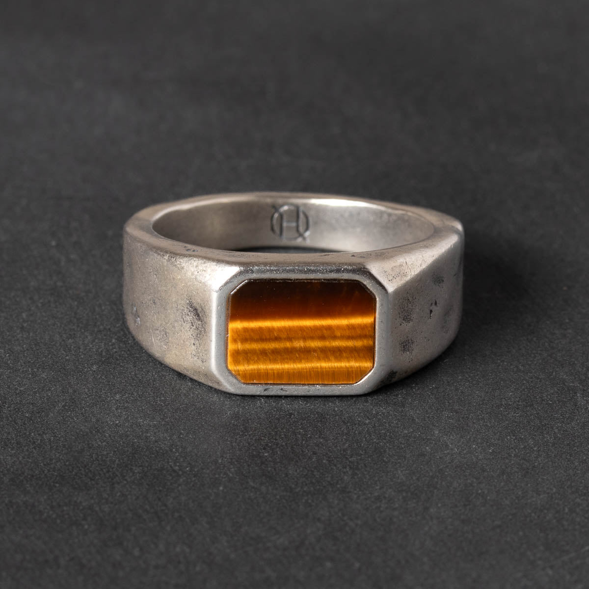 Silver ring with a tiger eye stone on a dark gray background