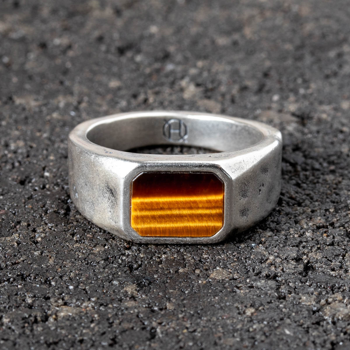 Silver ring with a square tiger's eye stone on a dark textured surface