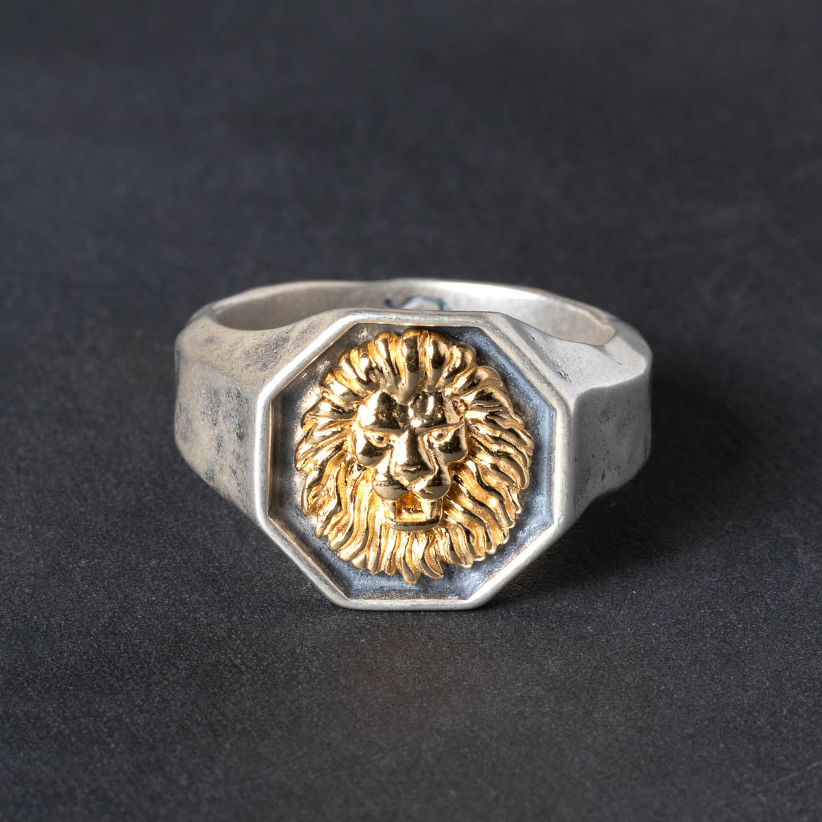 Octogon shaped Silver  signet ring with gold lion emblem on a dark background