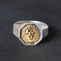 Octogon shaped Silver  signet ring with gold lion emblem on a dark background