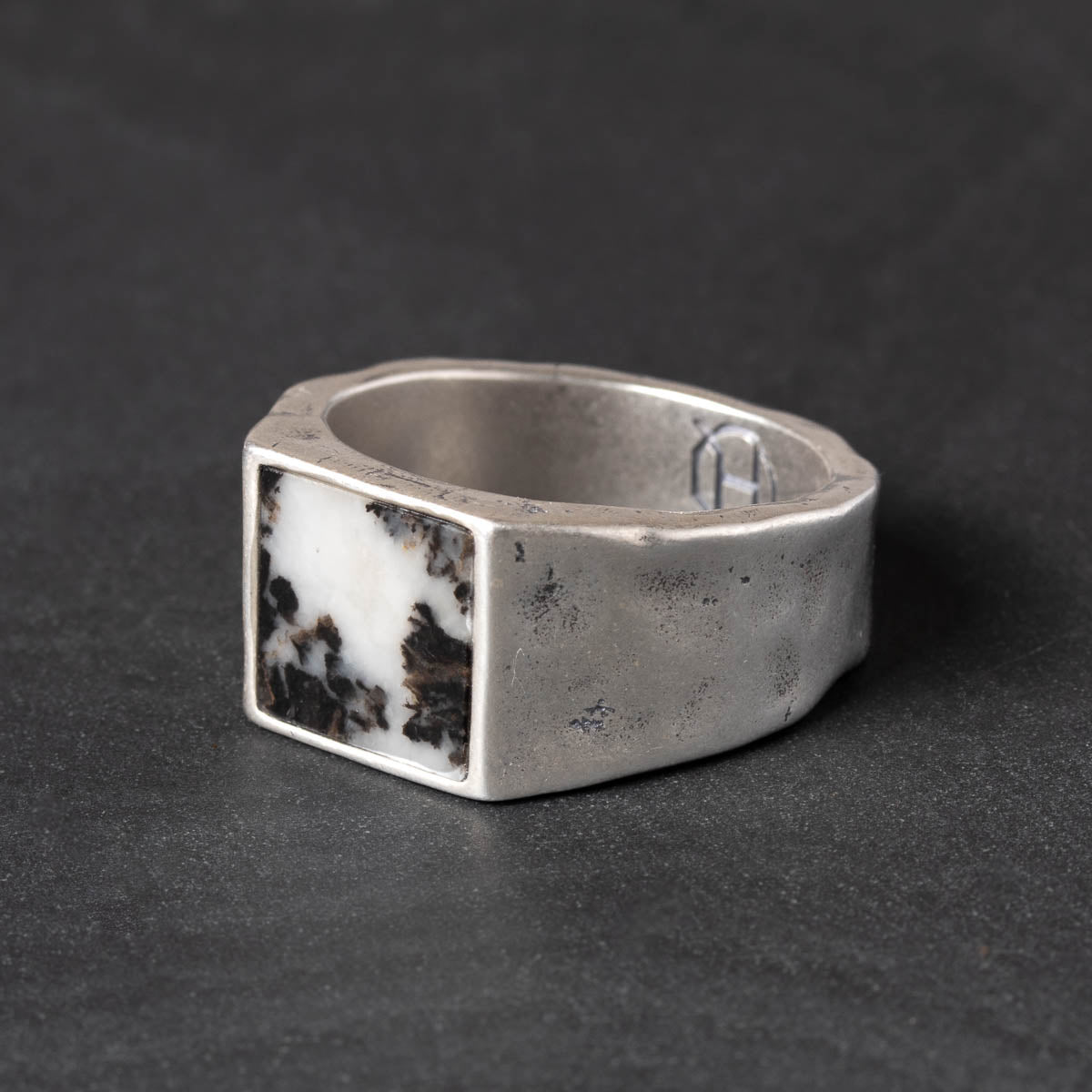 Silver ring with a square black & white zebra jasper stone inlay on a dark gray background