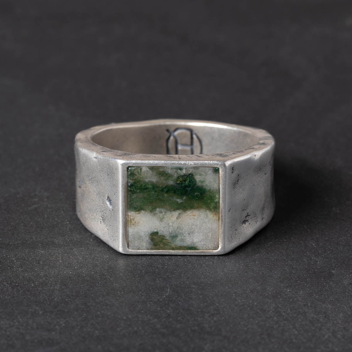 Silver ring with a square moss agate stone on a dark background