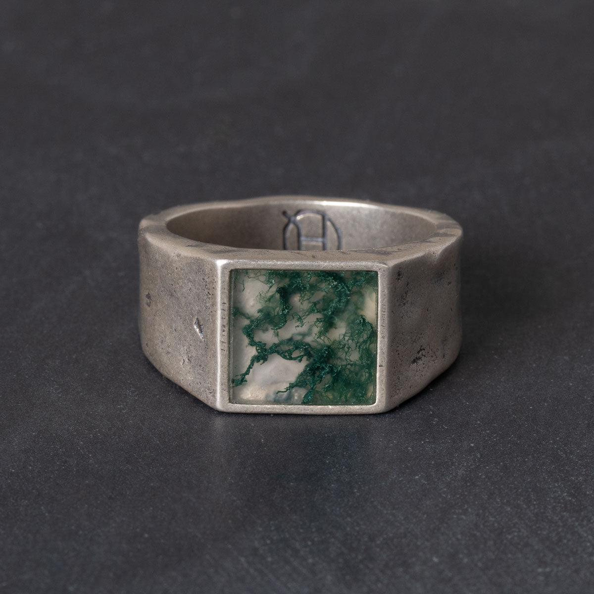 Silver ring with a square moss agate stone on a dark background