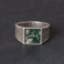 Silver ring with a square moss agate stone on a dark background