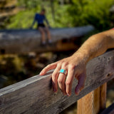 Man leaning on bridge railing with silver and turquoise ring