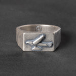 Silver ring with a 1950s hood ornament design on a dark background