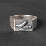 Silver ring with a 1950s hood ornament design on a dark background