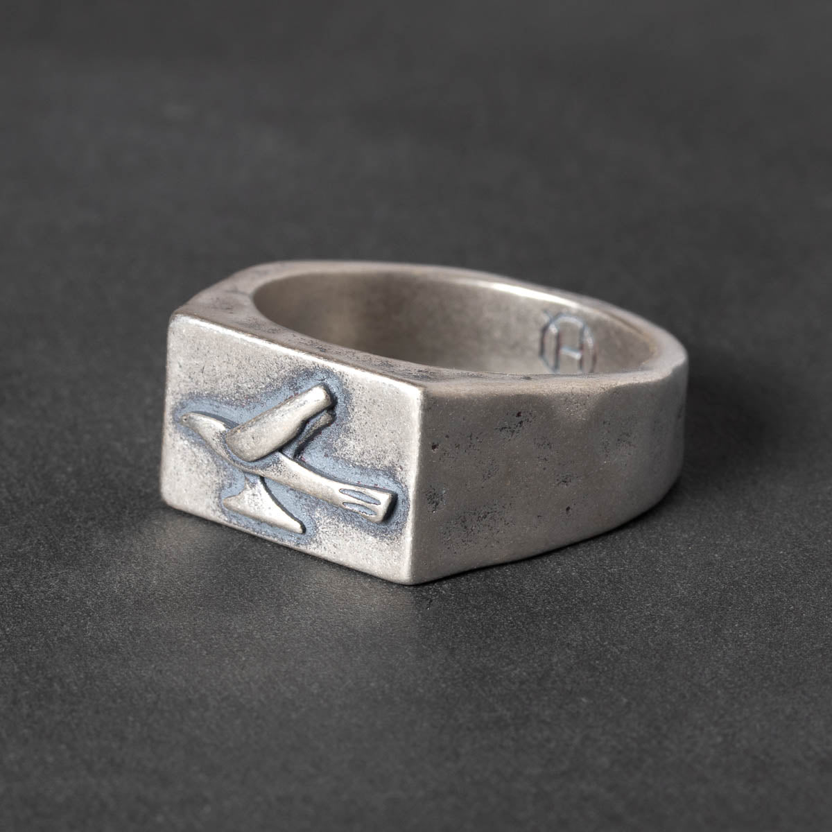 Silver signet ring with a 1950s hood ornament design on a dark background