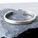 Silver cuff on a textured stone surface