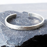 Silver cuff on a textured stone surface