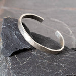 Silver cuff on a dark stone surface