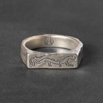 Silver ring with engraved stylistic panther design on a dark gray background