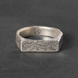 Silver ring with engraved stylistic panther design on a dark gray background