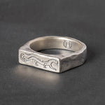 Silver signet ring with engraved stalking panther design on a dark gray background