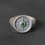 round Silver signet ring with compass design and green emerald cabochon on a dark background