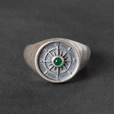 round Silver signet ring with compass design and green emerald cabochon on a dark background