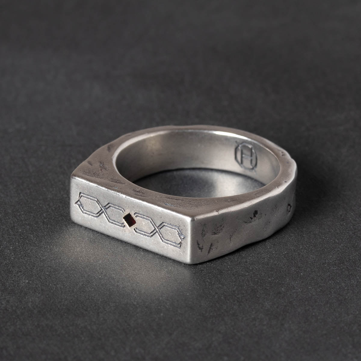 Silver ring with ouroboros carved design on a dark gray background