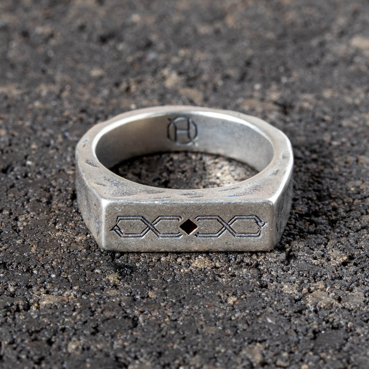 Silver ring with engraved design on a dark textured surface