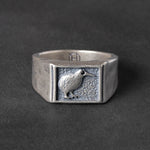 Textured silver signet ring with a kiwi bird carving on a dark background