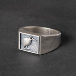 Silver ring with a kiwi bird emblem on a dark background
