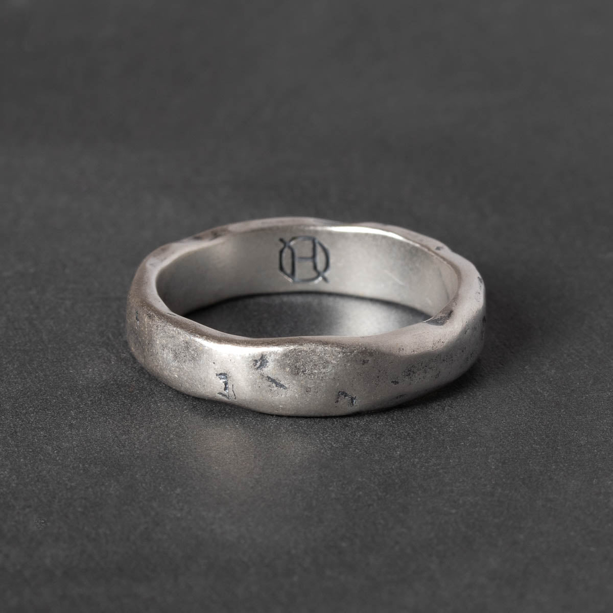 Silver band with textured motif  on a dark gray background