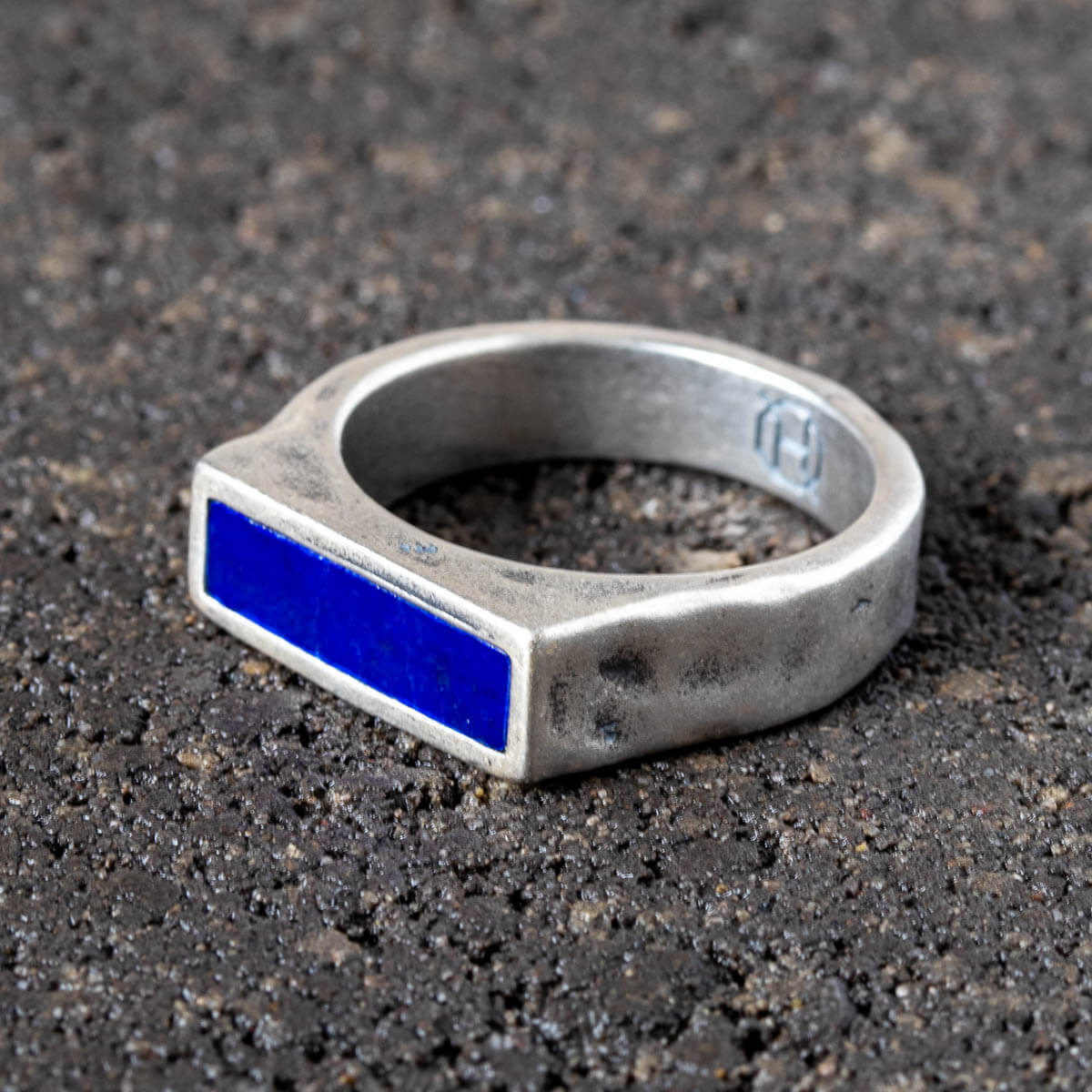 Silver ring with a blue lapis stone on  a dark textured surface
