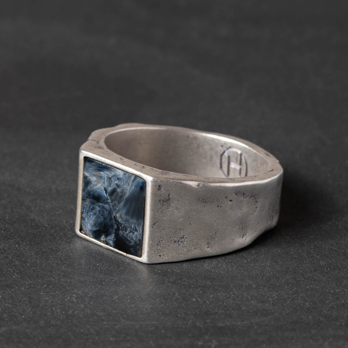 Silver ring with a slate blue pietersite stone inlay on a dark background