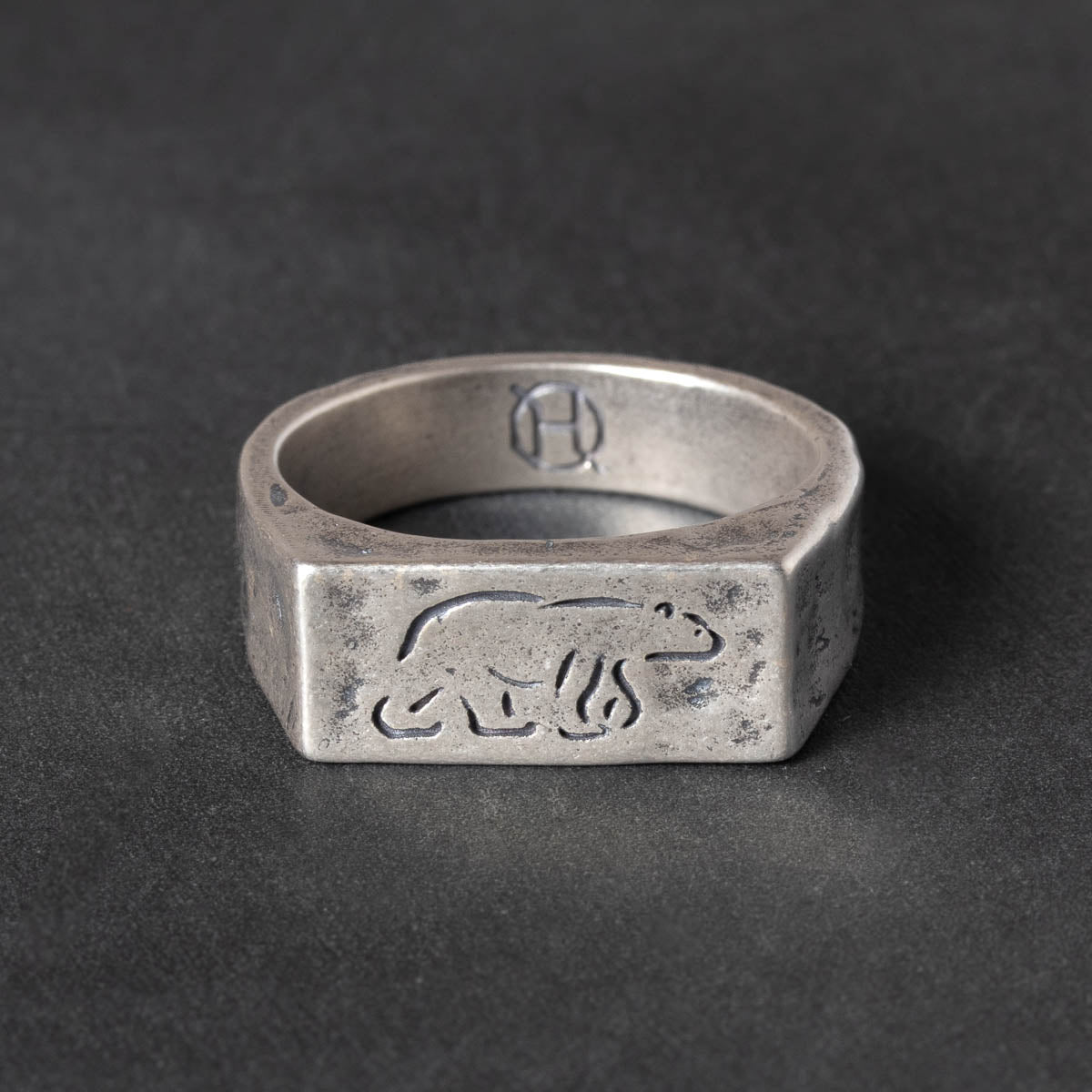 Silver ring with engraved polar bear design on a dark gray background