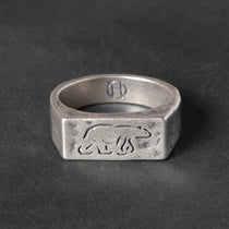 Silver ring with engraved polar bear design on a dark gray background
