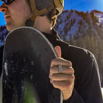 Person holding a snowboard with a mountainous background
