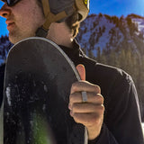 Person holding a snowboard with a mountainous background