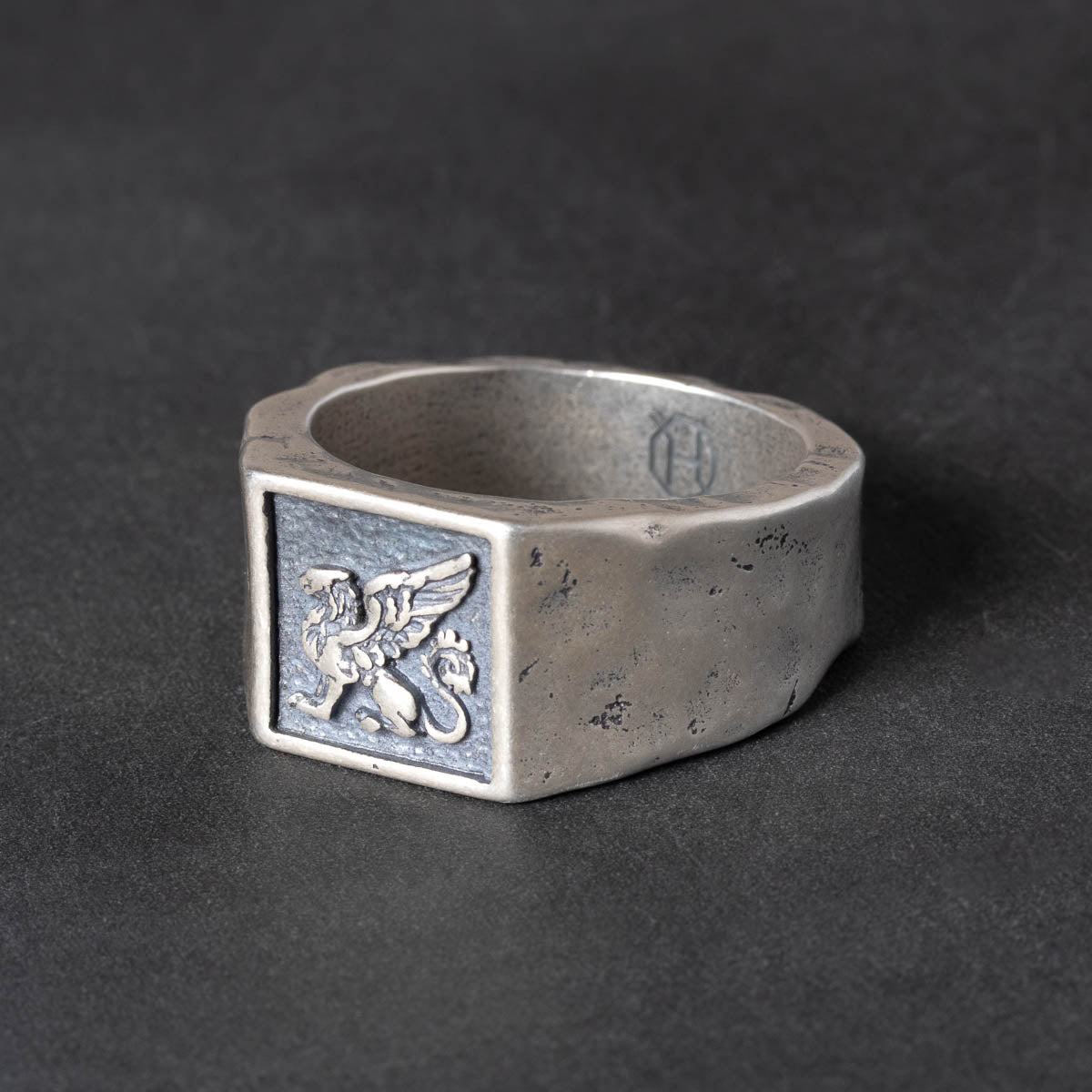 Rugged Silver signet ring with a griffin carving on a dark background