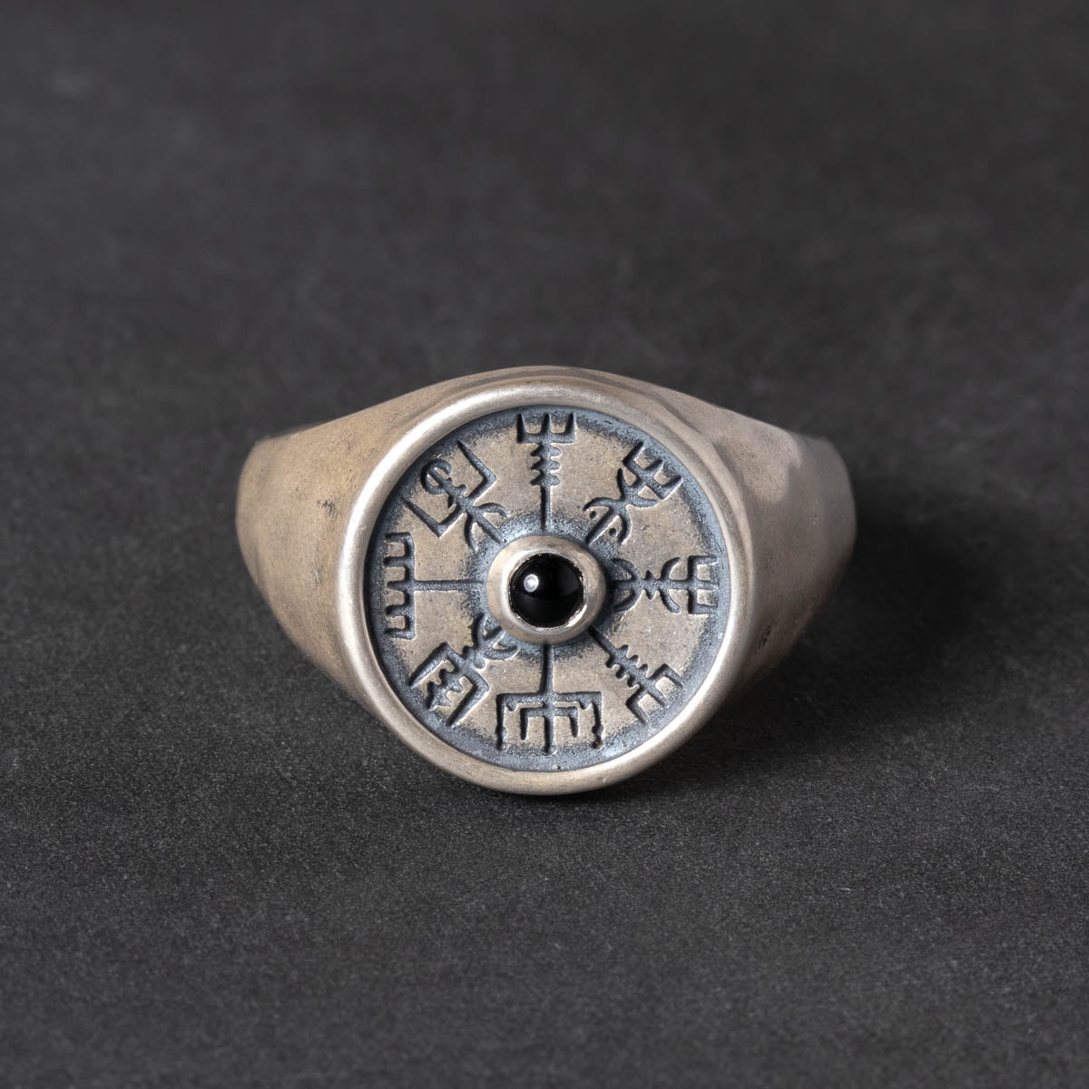 Silver signet ring with a vegvisir design and black onyx stone on a dark background