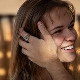 Man stroking woman's hair away from her face while wearing silver ring.