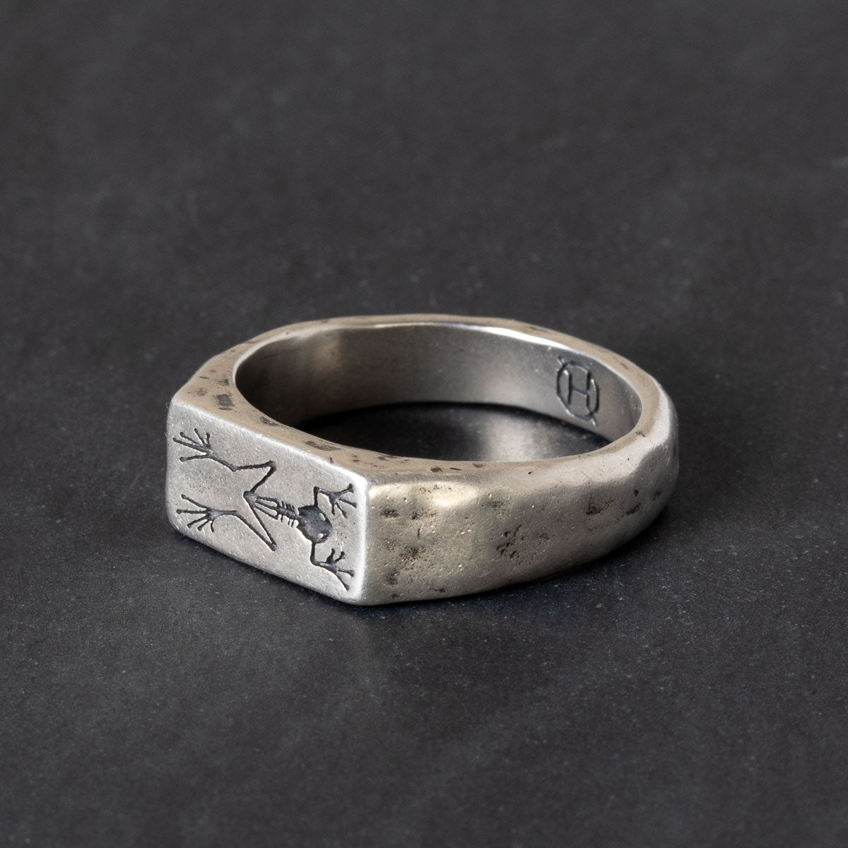 A Quinn Henry Sterling silver signet ring with engraved frog fossil skeleton.