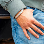 Hand hooked on blue jean pocket wearing a silver ring and silver cuff.